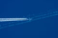 Transportation competition concept: a jet airplane crossing other planeÃ¢â¬â¢s white contrail against blue sky background Royalty Free Stock Photo